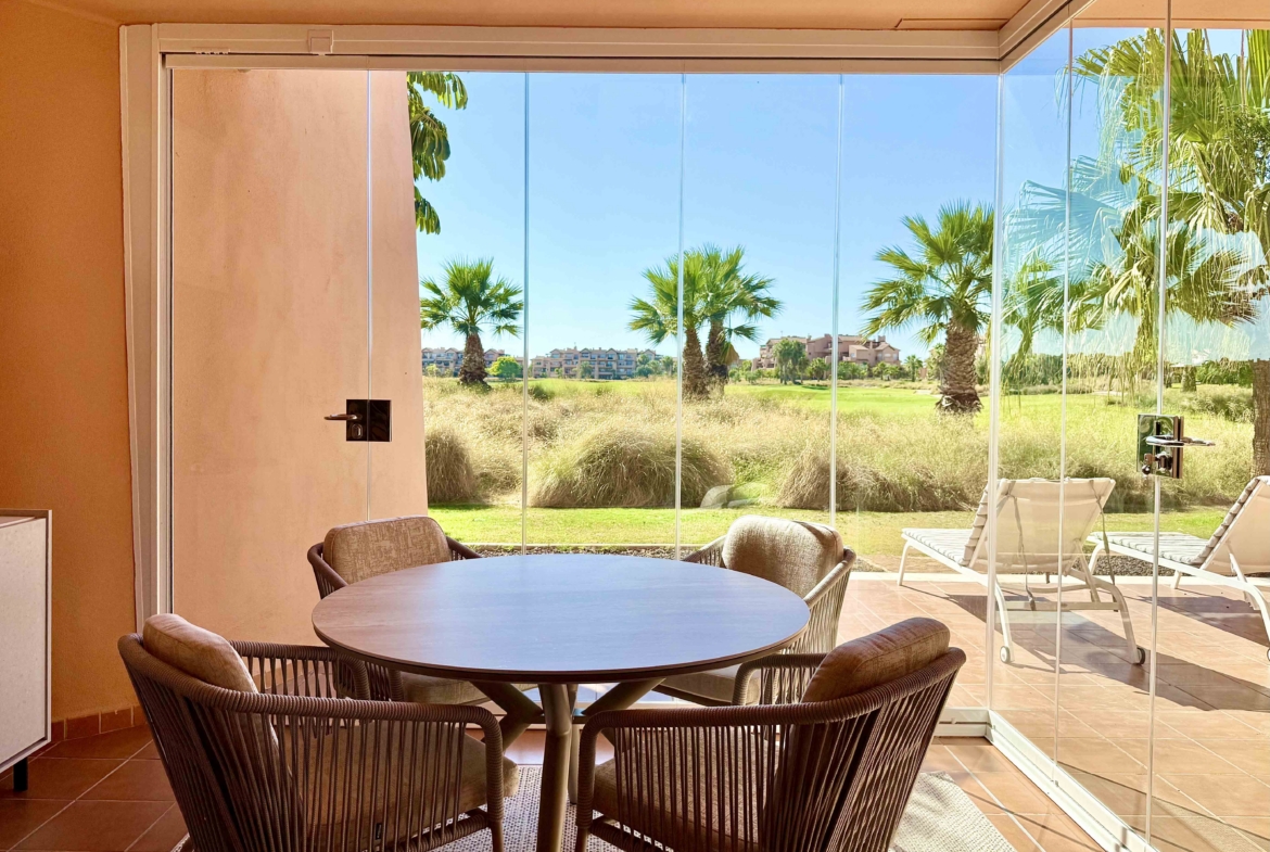 Enclosed terrace with glass curtains overlooking the golf course and lake at Mar Menor Golf Resort, exclusively marketed by Levante Properties.