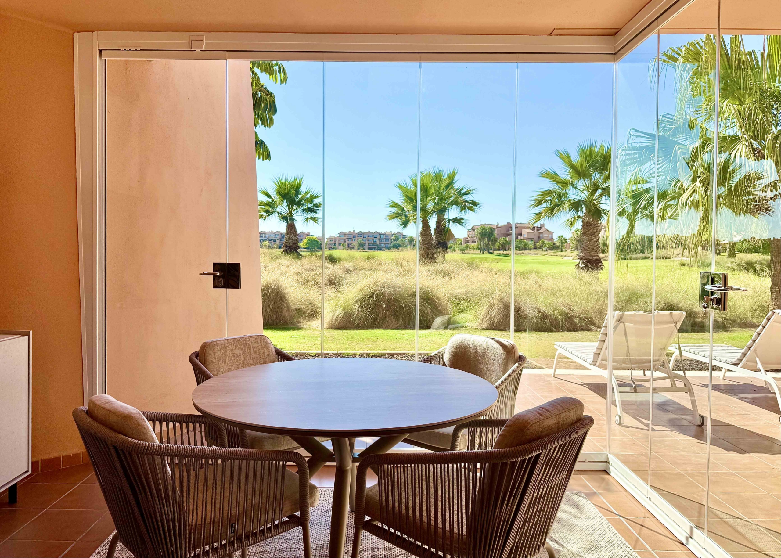 Enclosed terrace with glass curtains overlooking the golf course and lake at Mar Menor Golf Resort, exclusively marketed by Levante Properties.