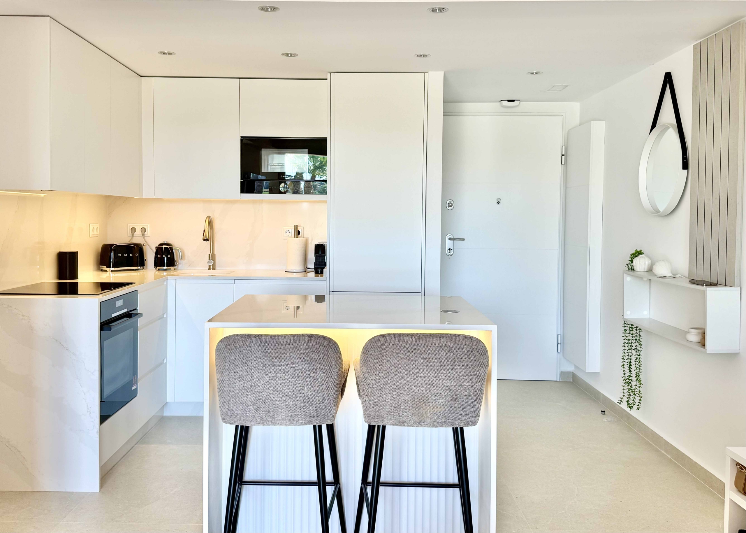 Modern white kitchen with breakfast island in an upgraded one-bedroom apartment for sale on Mar Menor Golf Resort by Levante Properties.
