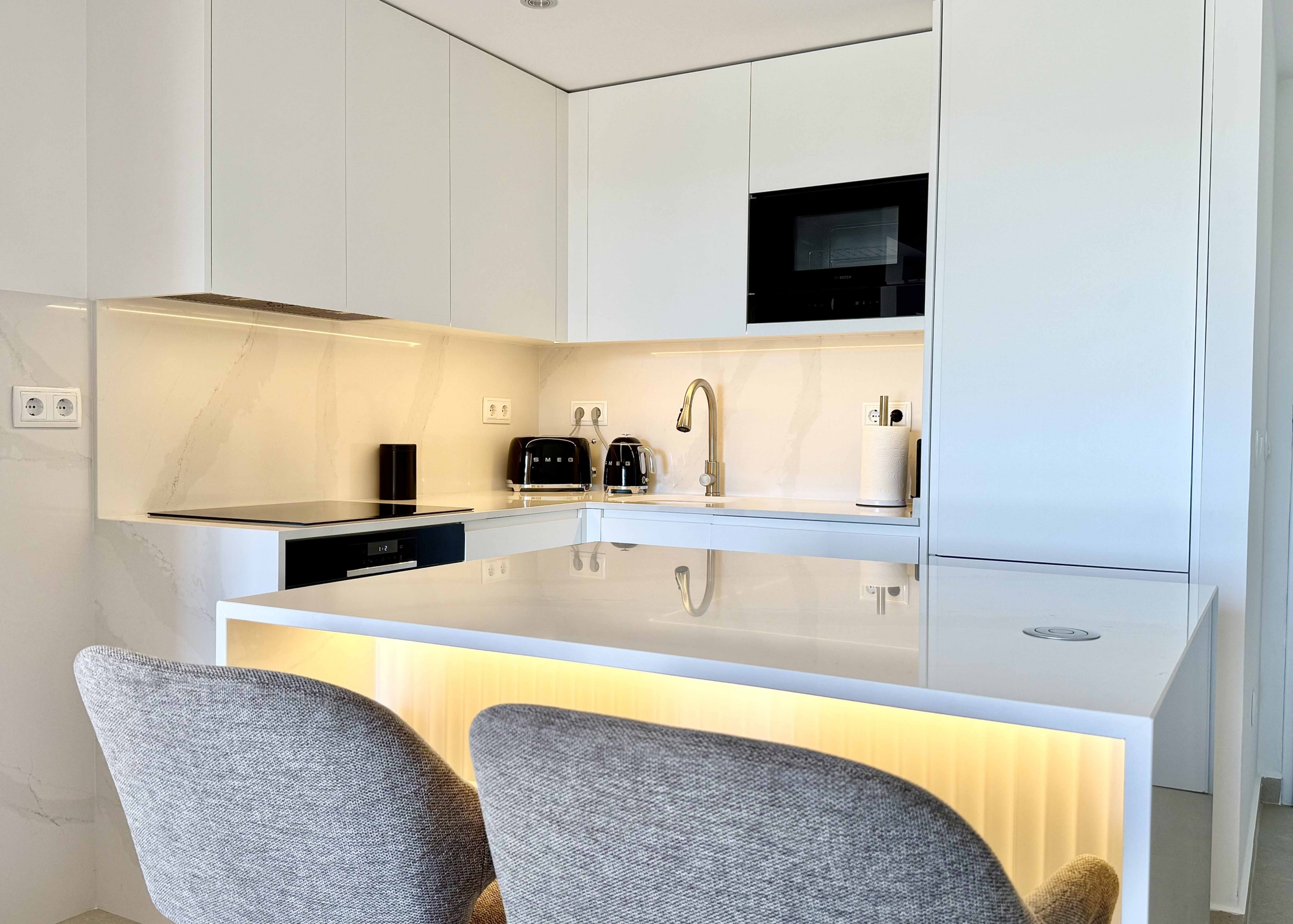Modern white kitchen with breakfast island in an upgraded one-bedroom apartment for sale on Mar Menor Golf Resort by Levante Properties.