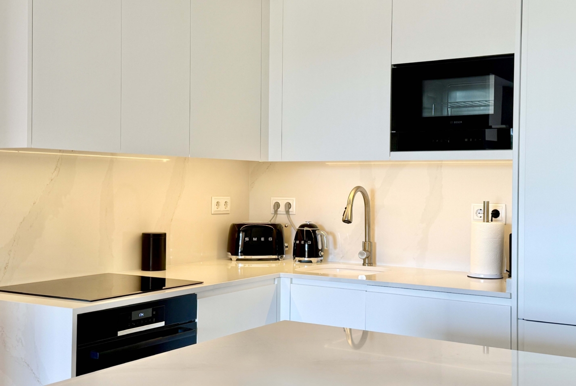 Modern white kitchen with breakfast island in an upgraded one-bedroom apartment for sale on Mar Menor Golf Resort by Levante Properties.