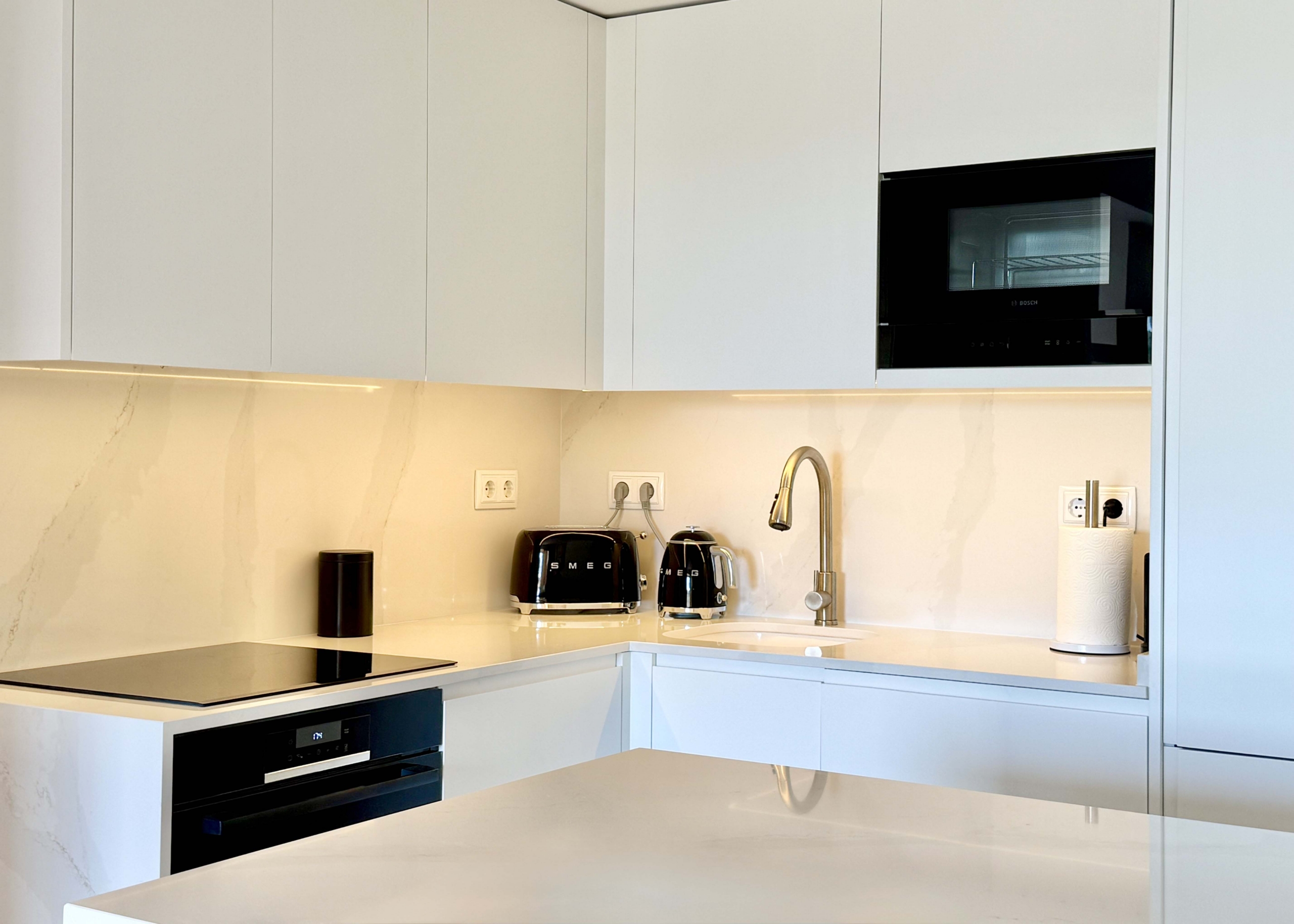 Modern white kitchen with breakfast island in an upgraded one-bedroom apartment for sale on Mar Menor Golf Resort by Levante Properties.